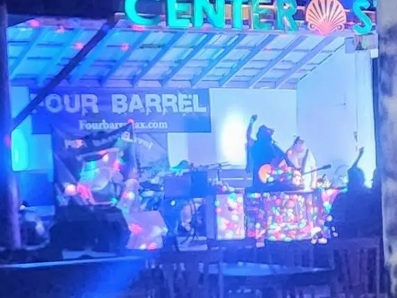 Night performance under a pavilion with colored lights and a Four Barrel banner